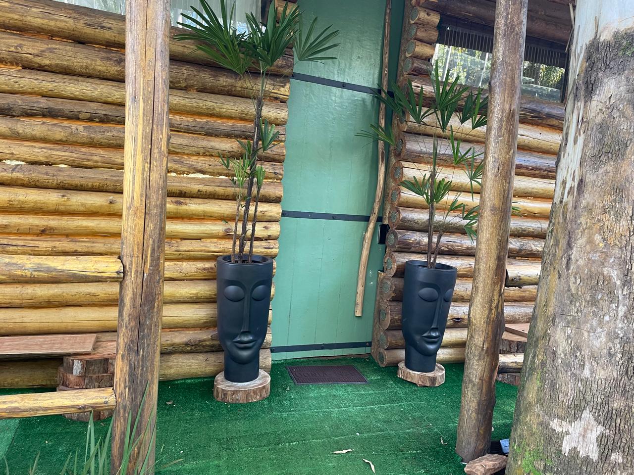 Os dois vasos pretos com rostos que ficam na entrada da cabana